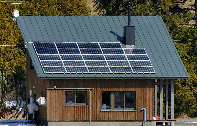 美瑛の丘を背にして建つ片流れ屋根のお住まい。南に傾斜した屋根に7.9kWの太陽光発電パネルが設置されている
