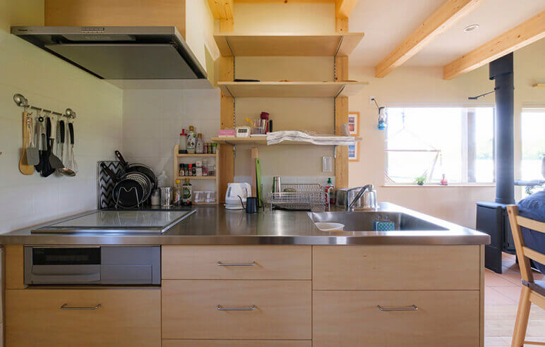 ステンレス天板のオリジナルキッチン。標準的なI型キッチンより横幅が短めだが奥行きが深く、よく使う調理器具や調味料を手元に置いても邪魔にならない